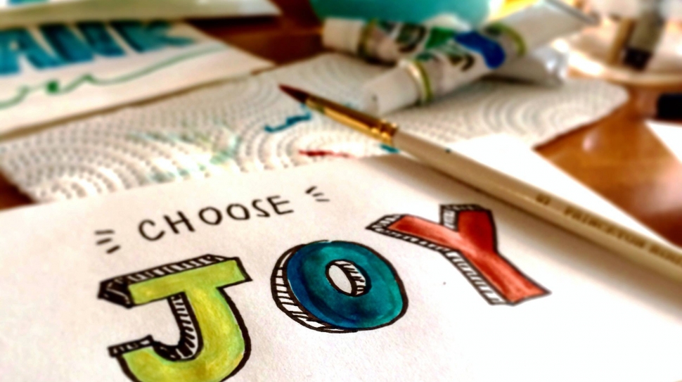 A painting of the words "choose joy" in bright green, red, and blue.