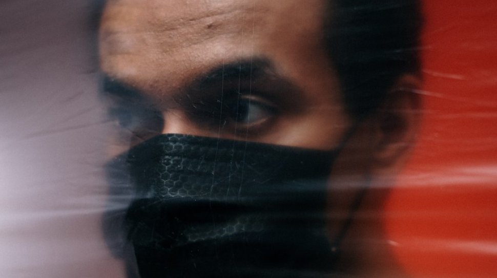 a man in a mask behind a plastic barrier