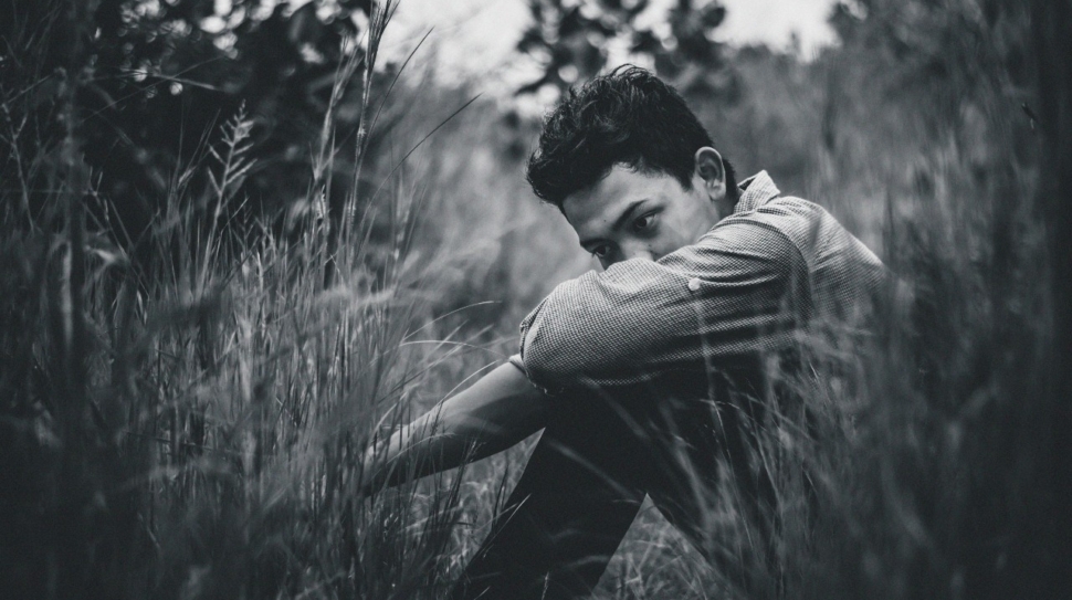 A man sits in a field, lost in thought