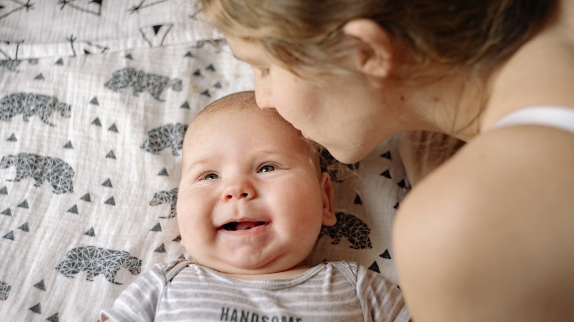 A mother kisses her baby on the forehead.