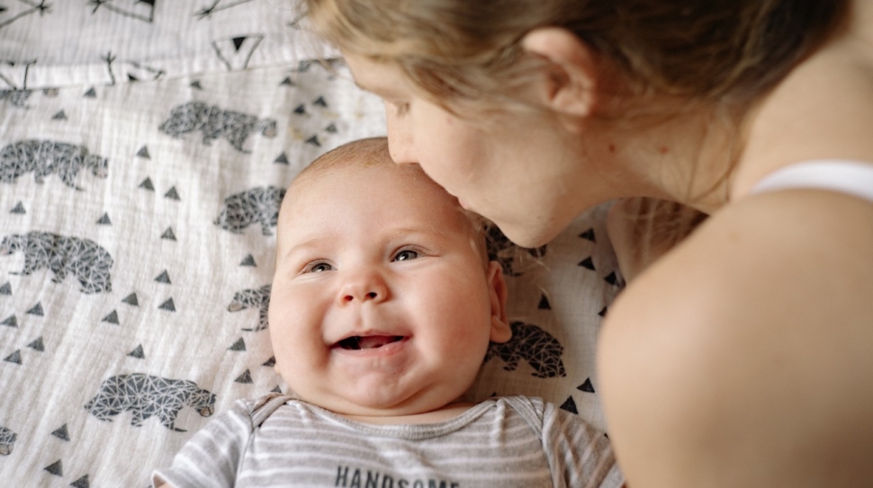 A mother kisses her baby on the forehead.